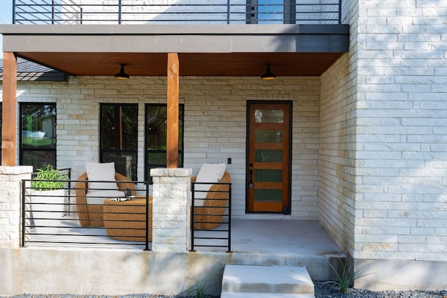 doorway to property with a balcony and a porch