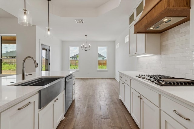 kitchen featuring custom exhaust hood, appliances with stainless steel finishes, pendant lighting, and white cabinets