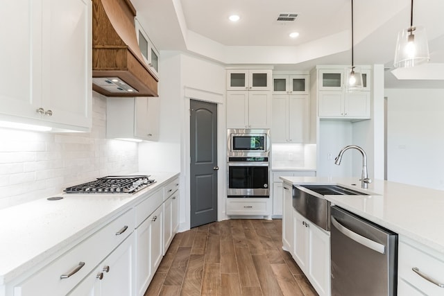 kitchen with stainless steel appliances, white cabinetry, hanging light fixtures, and custom range hood