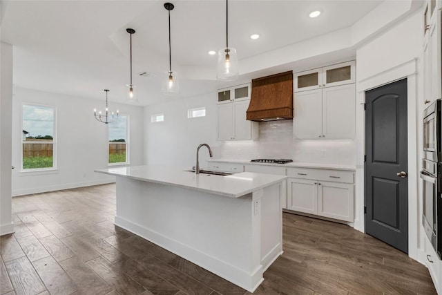 kitchen featuring sink, white cabinetry, gas cooktop, an island with sink, and custom range hood