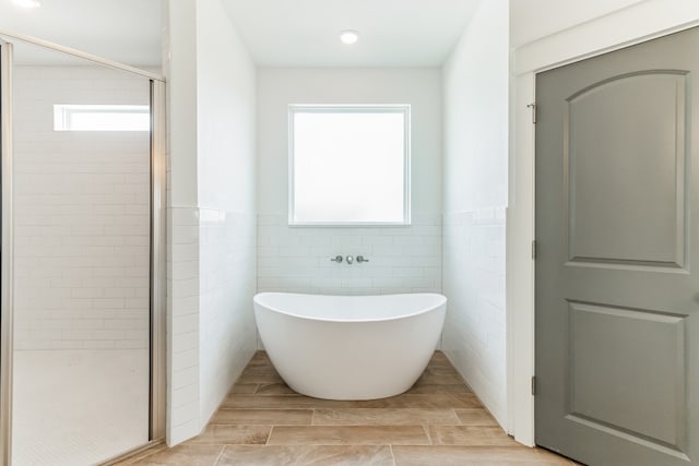 bathroom featuring separate shower and tub and tile walls