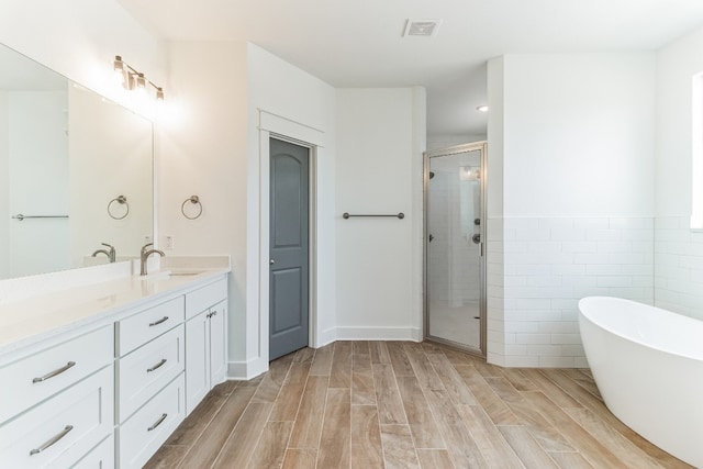 bathroom featuring plus walk in shower, tile walls, and vanity