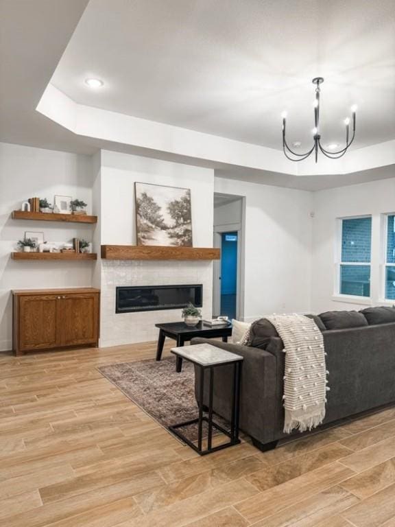 living room featuring a notable chandelier, a tray ceiling, and light hardwood / wood-style floors