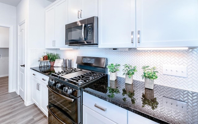 kitchen with dark stone counters, black range with gas cooktop, tasteful backsplash, light hardwood / wood-style flooring, and white cabinets