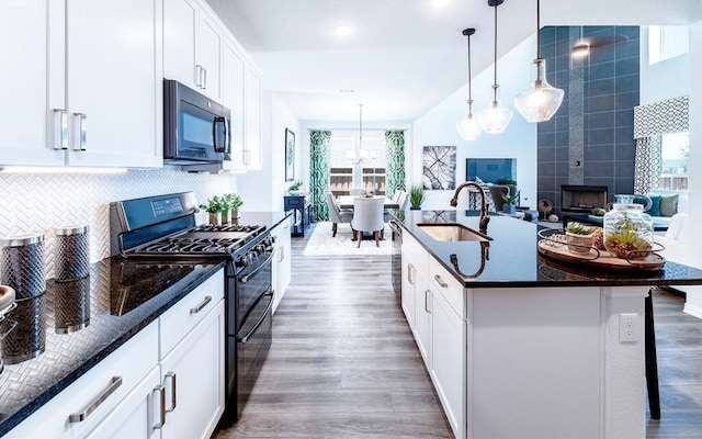 kitchen with double oven range, dark wood-type flooring, sink, and a center island with sink