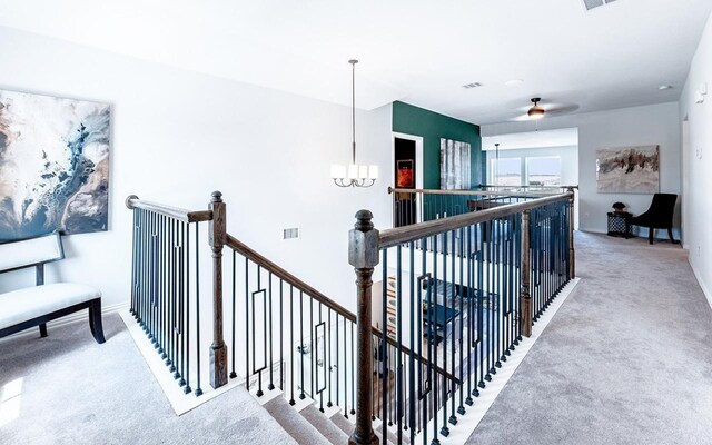 hallway with a chandelier and light colored carpet