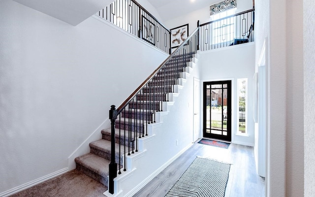 stairway with a high ceiling and light hardwood / wood-style floors