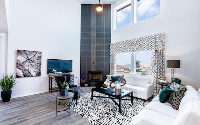 living room with a towering ceiling, a wood stove, wood-type flooring, and tile walls