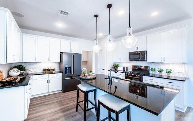 kitchen featuring hardwood / wood-style flooring, refrigerator with ice dispenser, tasteful backsplash, range with two ovens, and sink