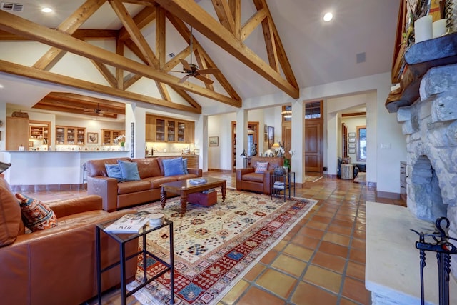 tiled living room featuring ceiling fan, beam ceiling, a fireplace, and high vaulted ceiling