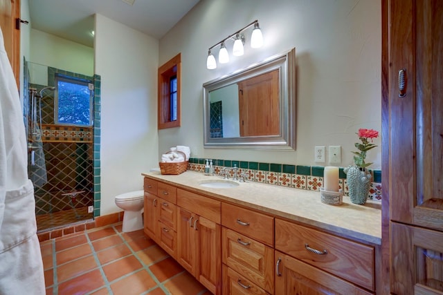 bathroom with tile floors, toilet, a tile shower, and vanity with extensive cabinet space