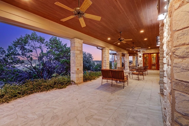 patio terrace at dusk featuring ceiling fan and french doors