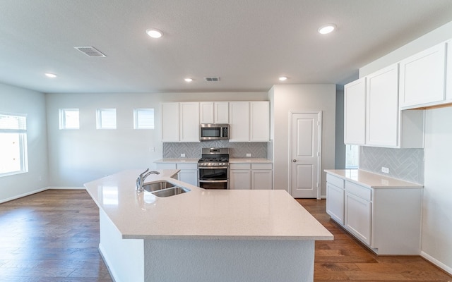 kitchen with appliances with stainless steel finishes, sink, hardwood / wood-style floors, and white cabinets