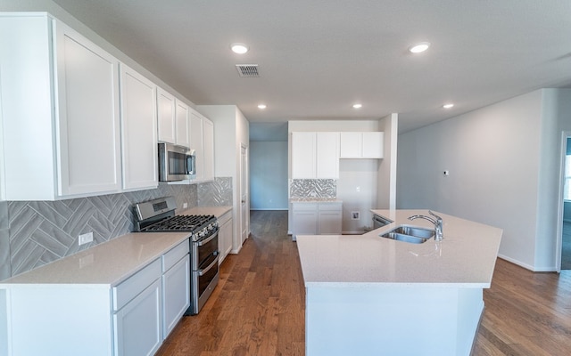 kitchen featuring tasteful backsplash, stainless steel appliances, dark hardwood / wood-style flooring, sink, and a center island with sink