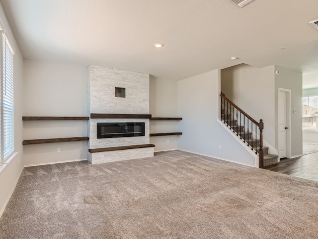 unfurnished living room with a stone fireplace and dark hardwood / wood-style flooring