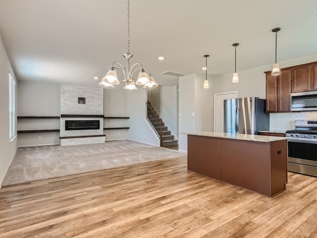 kitchen with hanging light fixtures, light hardwood / wood-style flooring, appliances with stainless steel finishes, and a fireplace