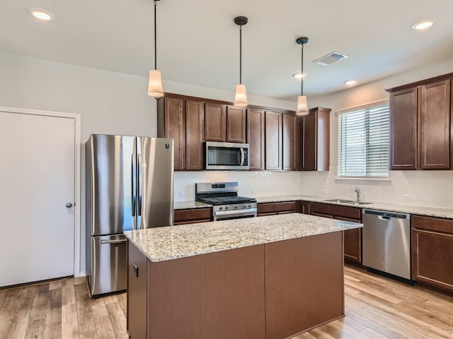 kitchen featuring pendant lighting, light wood-type flooring, appliances with stainless steel finishes, and a center island