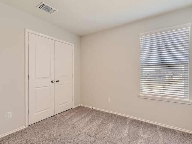 unfurnished bedroom with a closet and light colored carpet