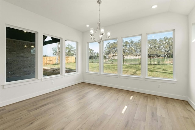 unfurnished dining area featuring lofted ceiling, a healthy amount of sunlight, light hardwood / wood-style flooring, and an inviting chandelier