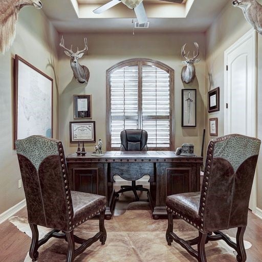 office space featuring a tray ceiling, light hardwood / wood-style floors, and ceiling fan