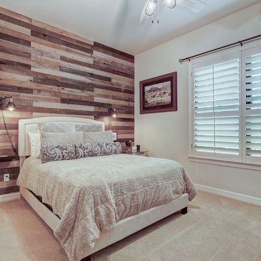 carpeted bedroom with wooden walls and ceiling fan