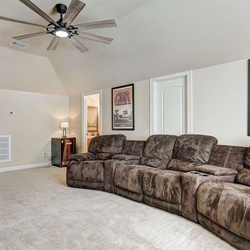 carpeted living room featuring ceiling fan and vaulted ceiling