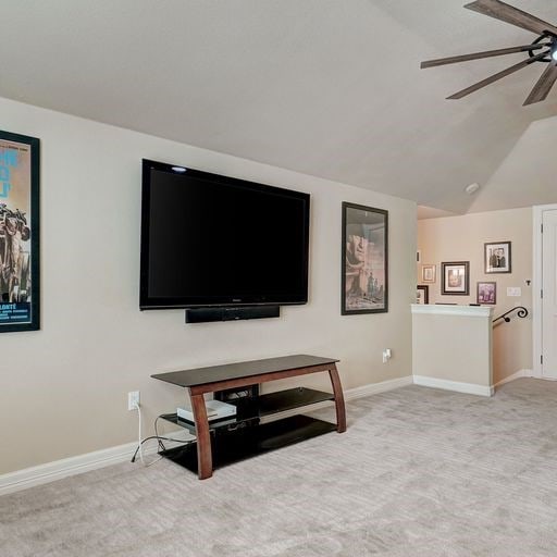 carpeted living room featuring ceiling fan and lofted ceiling