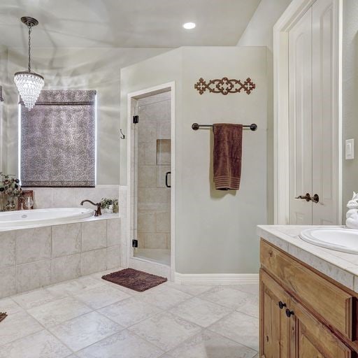 bathroom with a notable chandelier, vanity, tile floors, and independent shower and bath