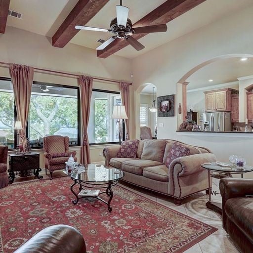 living room with light tile floors, beam ceiling, ceiling fan, and a wealth of natural light