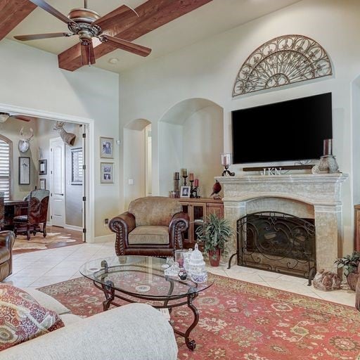 living room with light tile floors, ceiling fan, and beamed ceiling