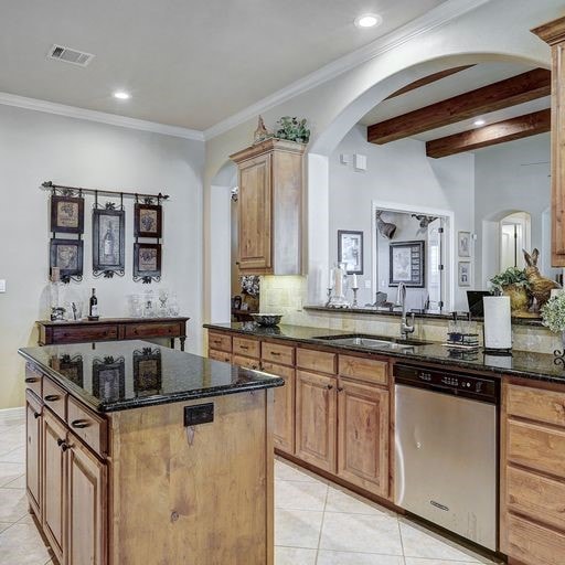 kitchen with light tile flooring, dark stone counters, sink, and dishwasher