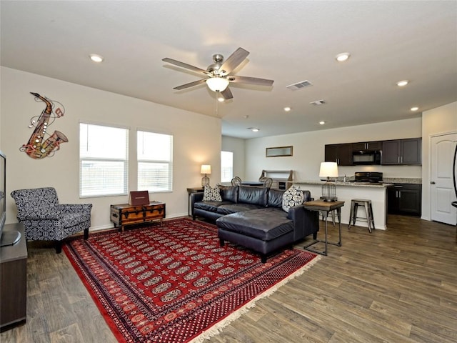 living room with dark wood-type flooring and ceiling fan