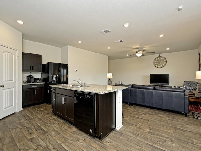 kitchen with dark brown cabinetry, sink, dark hardwood / wood-style flooring, a kitchen island with sink, and black appliances