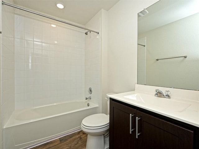 full bathroom featuring vanity, hardwood / wood-style floors, tiled shower / bath, and toilet