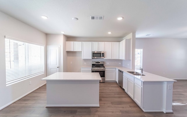 kitchen with white cabinets, stainless steel appliances, a healthy amount of sunlight, and backsplash