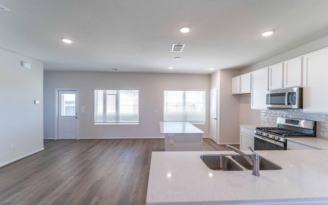 kitchen with appliances with stainless steel finishes, sink, backsplash, a kitchen island, and wood-type flooring