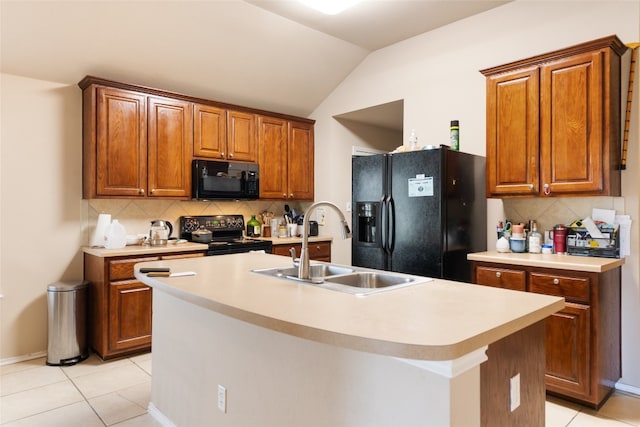 kitchen featuring tasteful backsplash, a kitchen island with sink, light tile floors, and black appliances