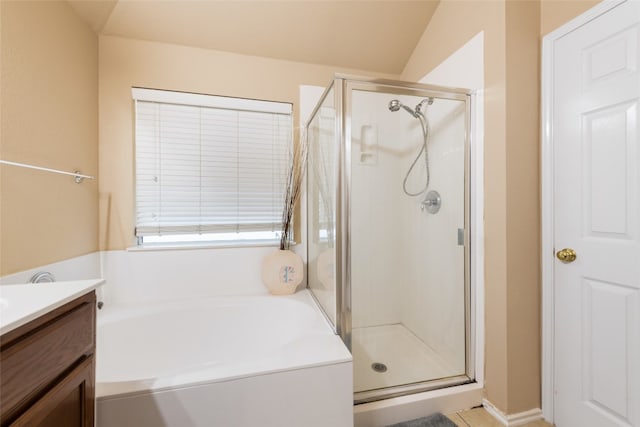 bathroom featuring vanity, independent shower and bath, and vaulted ceiling