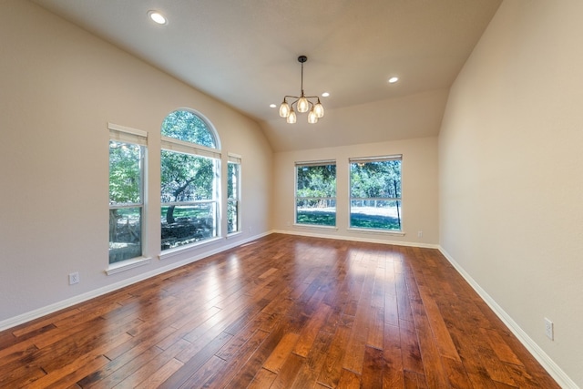 empty room with a wealth of natural light, vaulted ceiling, dark hardwood / wood-style floors, and an inviting chandelier