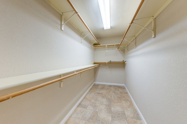 walk in closet with light tile floors