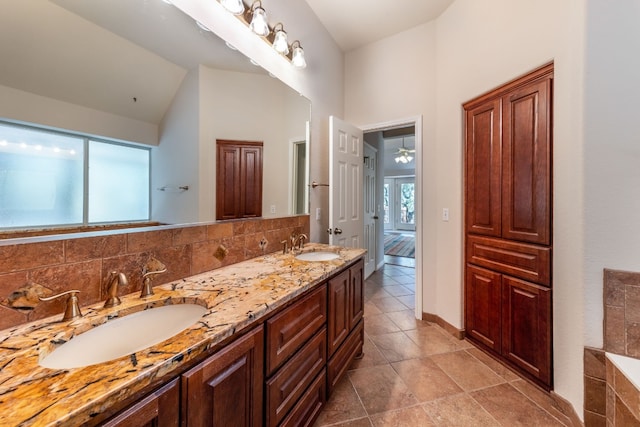 bathroom featuring tasteful backsplash, double vanity, a bath, lofted ceiling, and tile floors