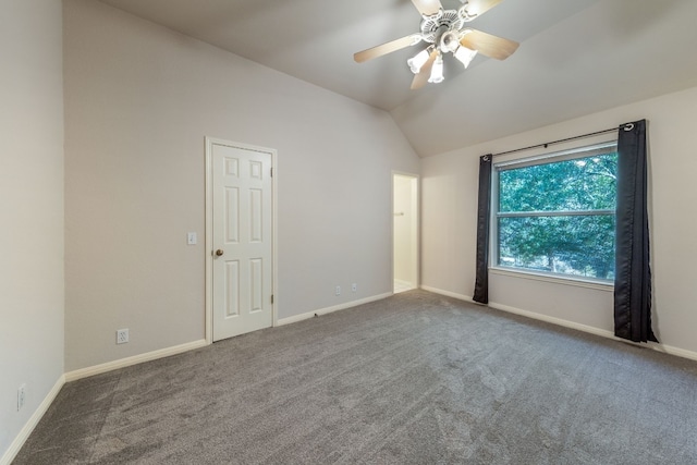 spare room with ceiling fan, dark colored carpet, and vaulted ceiling