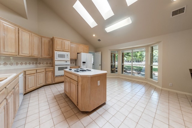 kitchen with a center island, white appliances, light tile floors, a skylight, and high vaulted ceiling