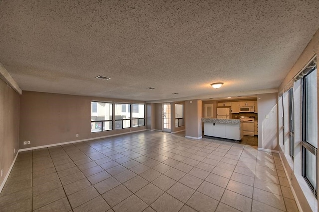 unfurnished living room featuring light tile patterned floors and a textured ceiling