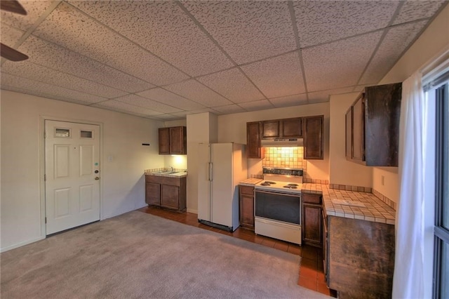 kitchen featuring a paneled ceiling, dark carpet, white appliances, sink, and decorative backsplash