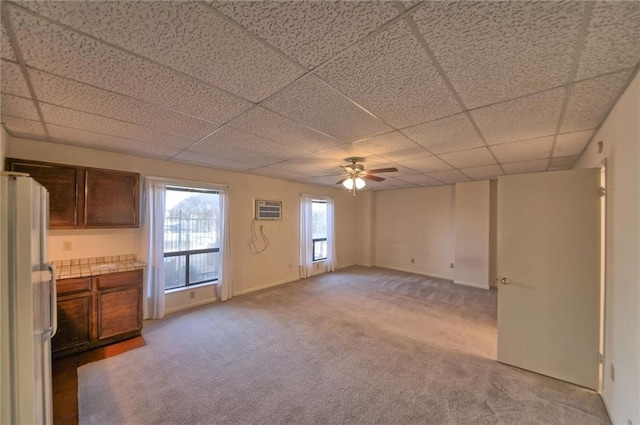 interior space featuring a wall unit AC, a paneled ceiling, and ceiling fan