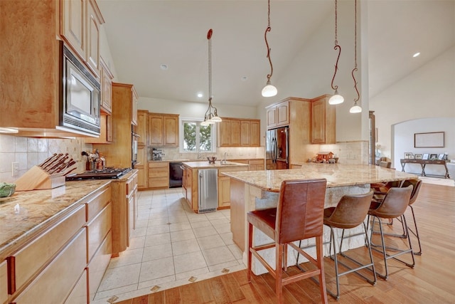 kitchen featuring a kitchen breakfast bar, kitchen peninsula, decorative backsplash, and appliances with stainless steel finishes