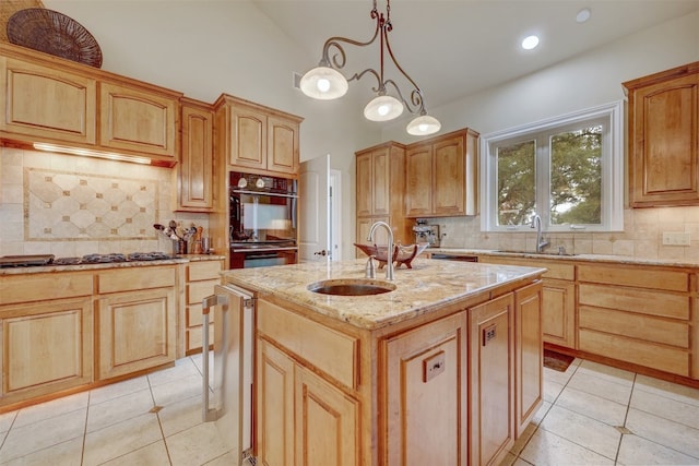 kitchen featuring backsplash, decorative light fixtures, sink, and an island with sink