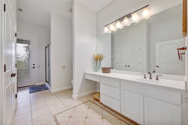 bathroom featuring tile patterned floors, vanity, toilet, and a shower with shower door