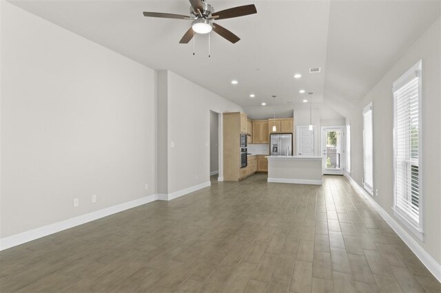 unfurnished living room featuring vaulted ceiling, hardwood / wood-style flooring, and ceiling fan